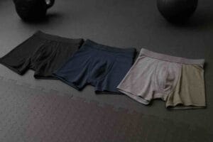 Miesten urheilualushousut vierekkäin kuntosalialustalla – polyesteri-, polyamidi- ja merinovillamallit.